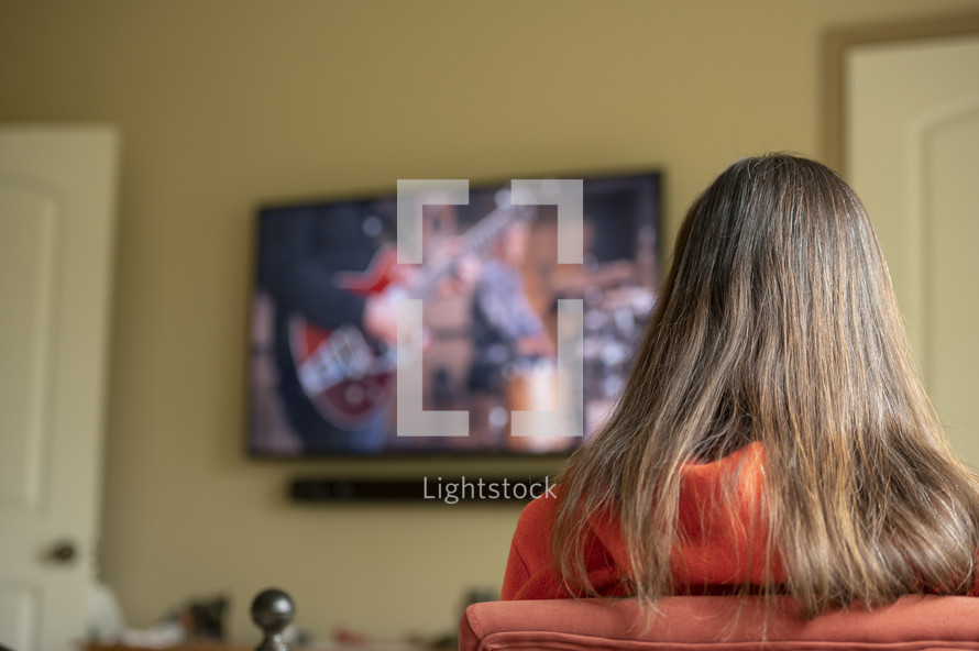 Woman watching a church service from home with Tv out of focus