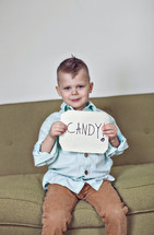 A boy child holding a sign that reads Candy