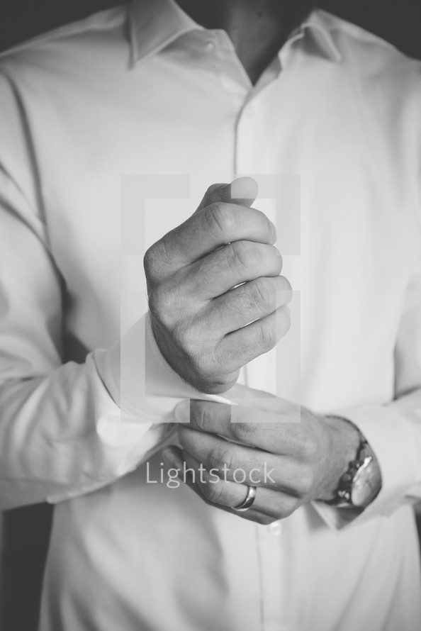 a groom fastening his buttons getting ready for his wedding 