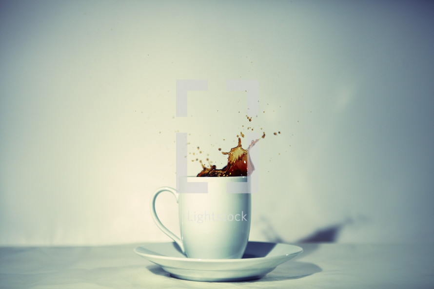 Coffee splashes out of a white coffee mug
