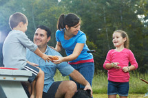 family eating hotdogs at a picnic table 