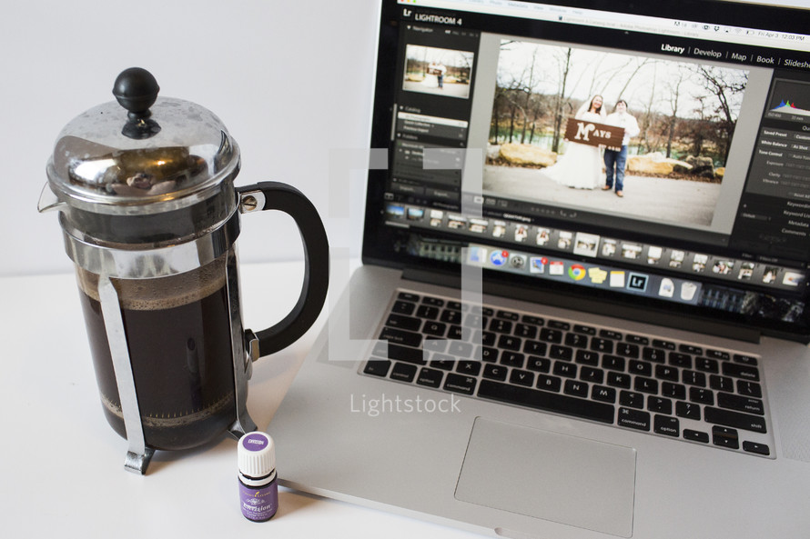 coffee press and laptop opened to wedding photos 