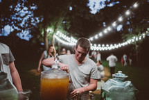 people gathered for an outdoors dinner party pouring drinks 