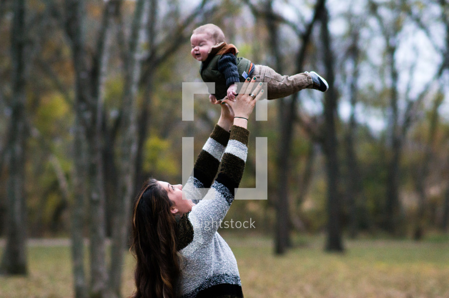 a mother tossing a baby in the air 