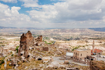 view of ruins in a man sitting at the edge of a cliff in Cappadocia