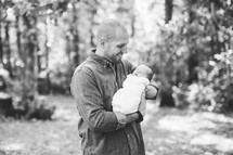 a father holding his newborn outdoors 