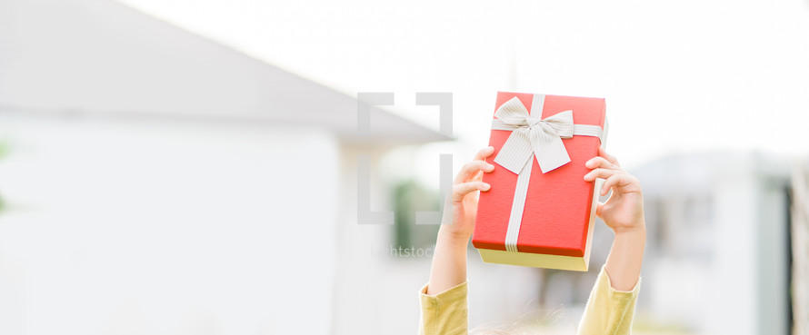 arms holding up a red Christmas gift 