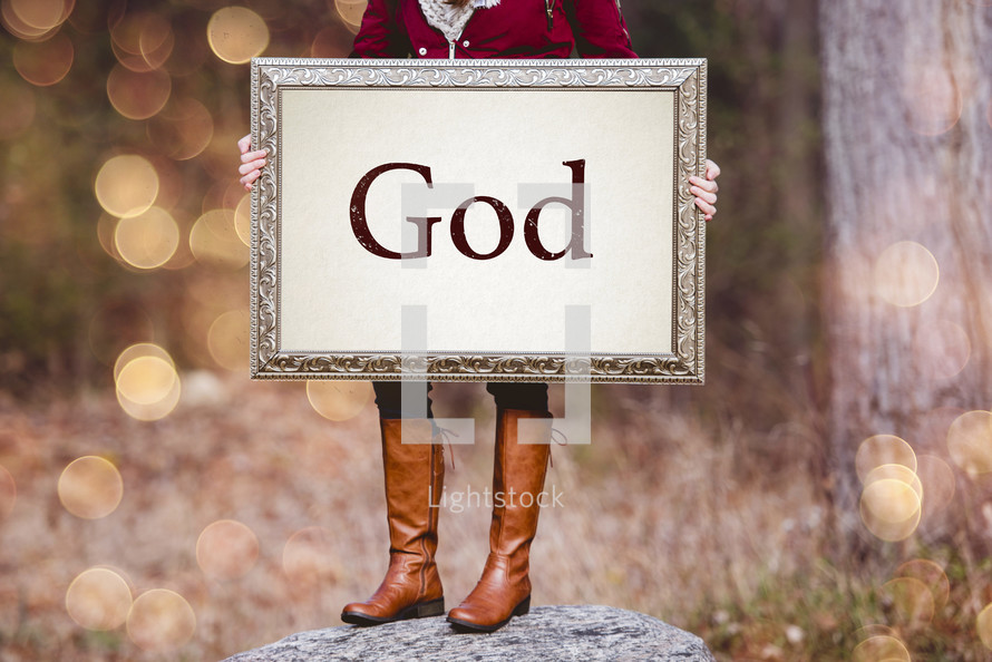 a woman holding a sign the reads God 