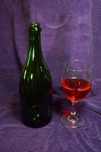 Wine bottle and glass with purple cloth background