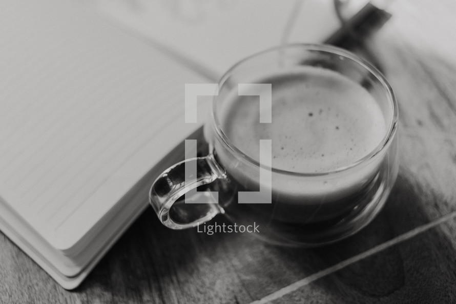 clear glass coffee cup and blank pages of a journal 