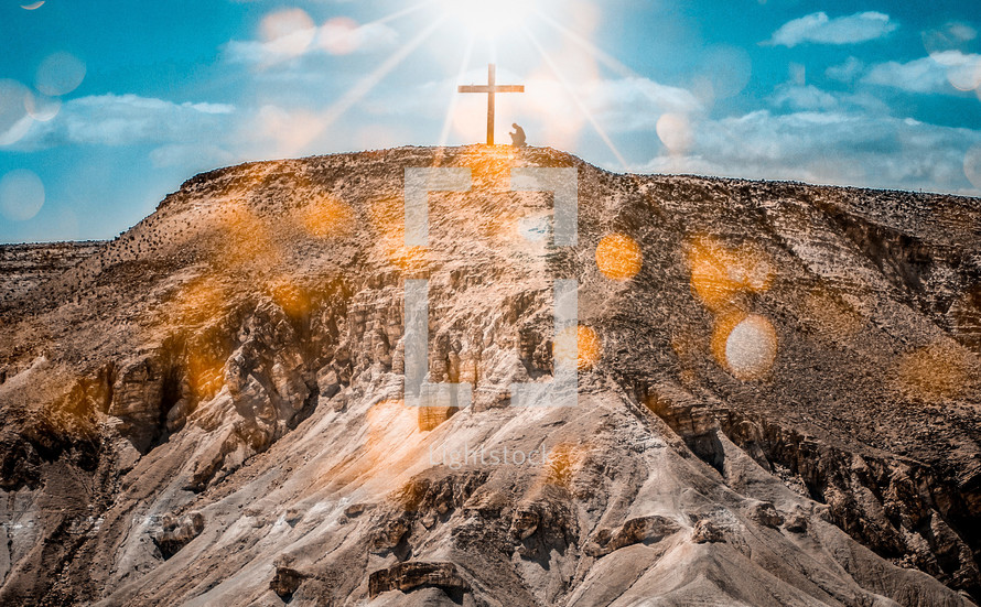 sunburst over a cross on a mountaintop 