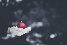 holding a red Christmas ornament
