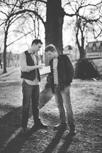 two men reading Bibles outdoors 
