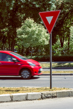 Yield sign near a crossroad with a red rushing car. Chromatic contrasts
