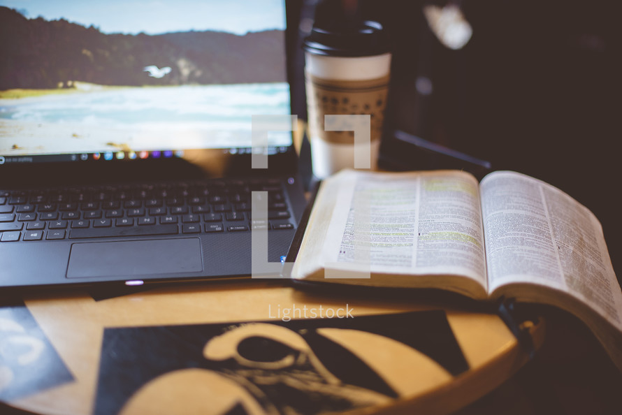 laptop computer, coffee cup, and opened Bible on a table 