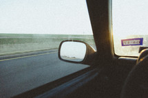 rear view mirror of a car on a road trip  