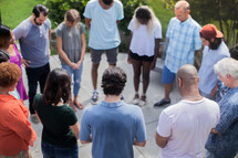 friends holding hands in prayer at a backyard summer party 