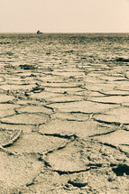 cracked earth and distant truck in a desert 