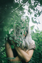a woman hiding behind leaves 
