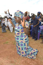 woman kneeling with arms raised in prayer