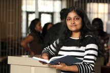 a college student standing holding a book 