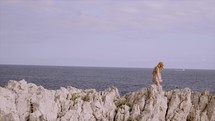 Girl climbing rocks near the seashore in South of France
