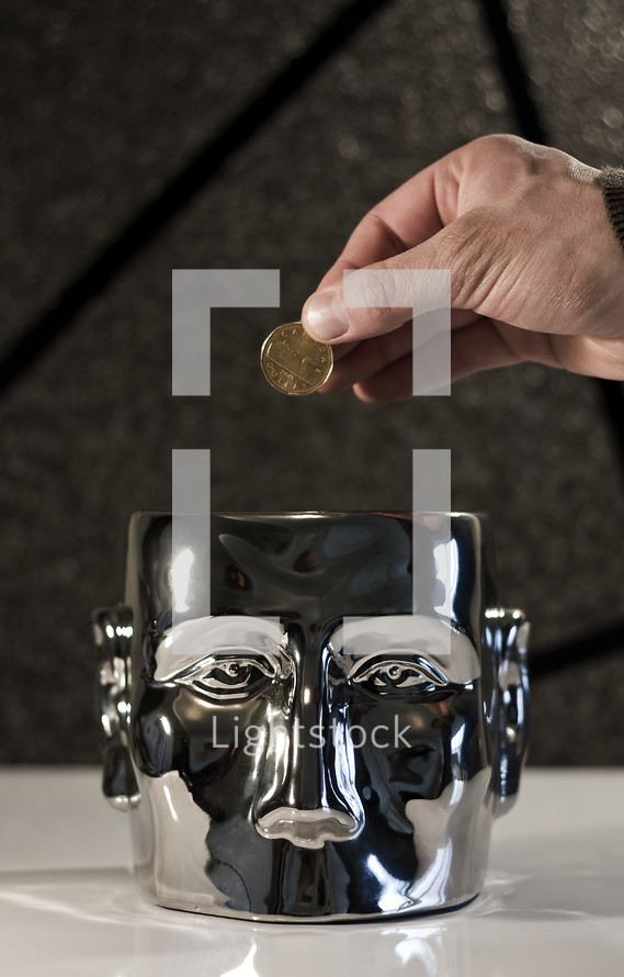 Mind on Money; hand holding coin (dollar) above a metal head.