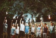 young adults holding up sparklers 