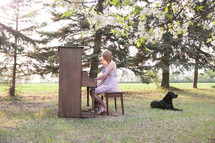 a woman playing a piano outdoors with her dog 