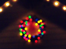 A colorful Christmas wreath lights up the night from a distance bringing light, warmth and cheer to a winter cold night at Christmas time. 