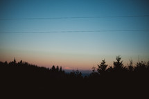 power lines over a hill silhouette at sunset 