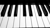 Black and white piano keys on a piano keyboard looking straight down the piano keyboard. 