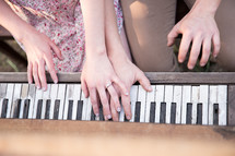 hands of a couple on the keys of a piano 
