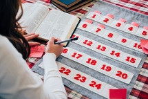 a woman stuffing Bible verses into an Advent calendar 