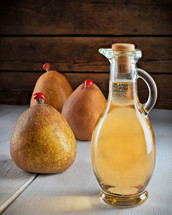 Small bottle vinegar of pears on wooden table.