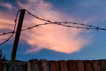Sunset behind barbed wire, private space.
