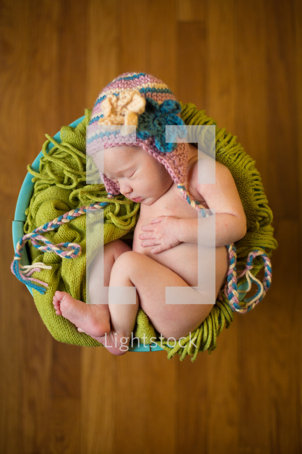 naked newborn in a hat in a basket