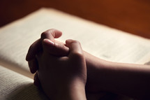 praying hands on a Bible 