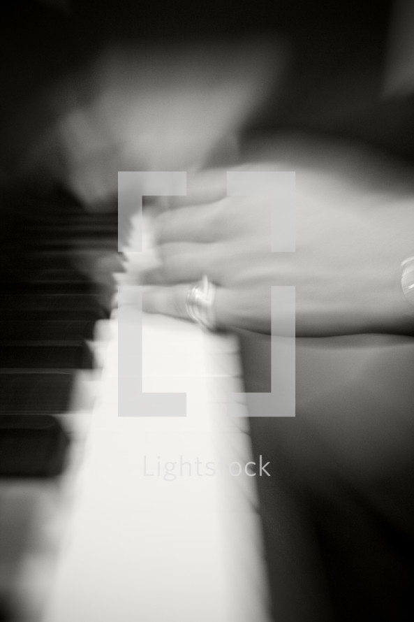 Man with ring on his pinky finger playing the piano.
