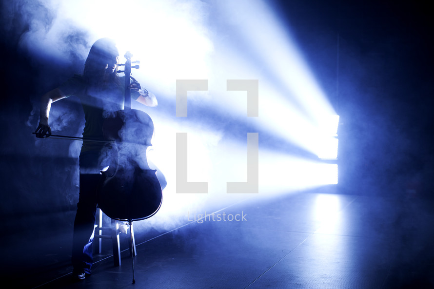 woman playing the cello under a spot light
