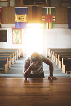 a man praying alone at an altar in a church 