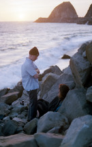 couple exploring a rocky coastline and stopping to rest 