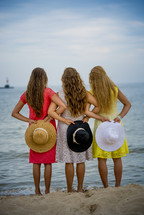 girls holding hat on a beach 