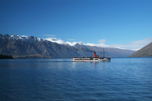 ferry boat crossing river with mountain range behind