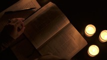 a woman reading a Bible by a candlelight 