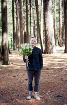 a man in a forest with a bouquet of flowers 