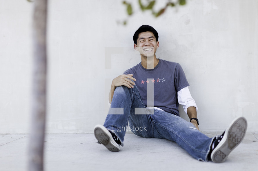 man sitting on a sidewalk laughing 