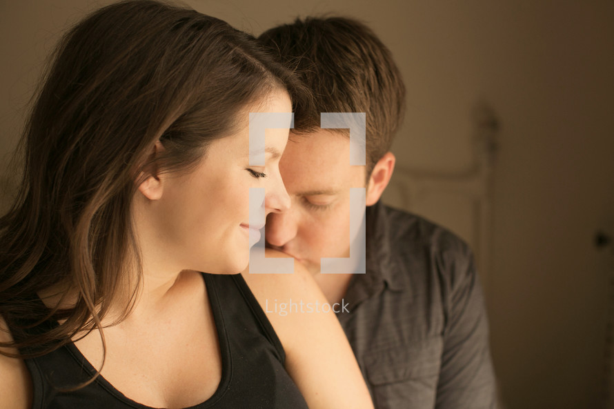 man kissing a woman's shoulder