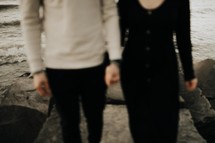 a couple standing on a shore holding hands 