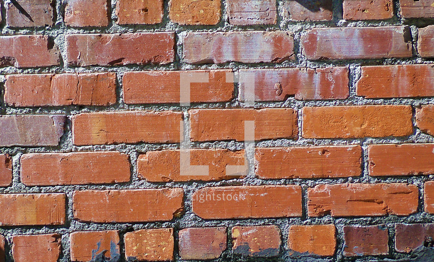 A red brick wall background showing bricks and mortar making a wall of bricks found in an urban downtown setting. 